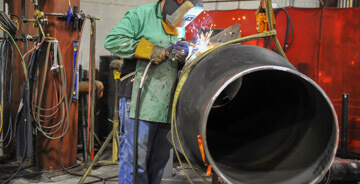 Man in safety gear working on a custom piping project